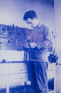 Un giovane artigiano al lavoro in un'officina con attrezzi appesi alla parete